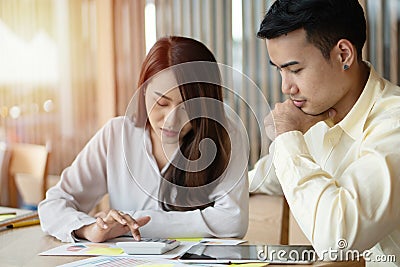 Unhappy Asian couples are calculating income And expenses To cut unnecessary expenses. Concepts for investment planning and financ Stock Photo