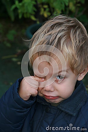 Unhappy child rubbing eye Stock Photo