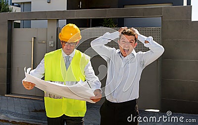 Unhappy customer in stress and constructor foreman worker with helmet and vest arguing outdoors on new house building blueprints Stock Photo
