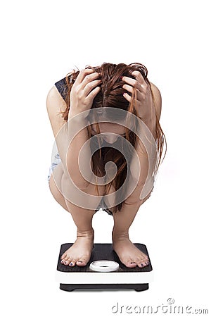 Unhappy girl squat on a weight scales Stock Photo
