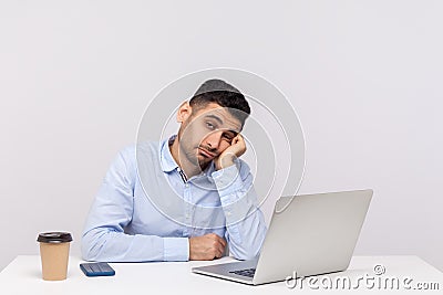Unhappy lazy inefficient man employee sitting office workplace with laptop on desk, looking disinterested Stock Photo