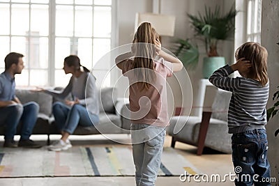 Unhappy little children looking at arguing parents. Stock Photo