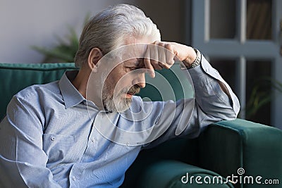 Unhappy lonely grey haired mature man sitting on couch Stock Photo