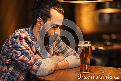 Unhappy lonely man drinking beer at bar or pub Stock Photo