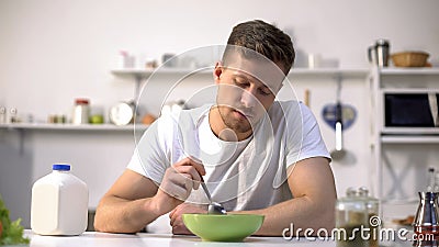 Unhappy lonely man looking with disgust at food in bowl, lack of appetite Stock Photo