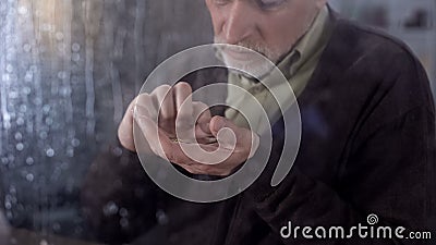 Unhappy male pensioner counting coins hand, old age poverty, social instability Stock Photo