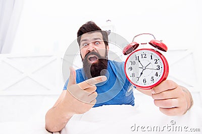 Unhappy man pointing at the alarm clock. hate noise of alarm clock. Man awake with retro alarm clock ringing. sick and Stock Photo