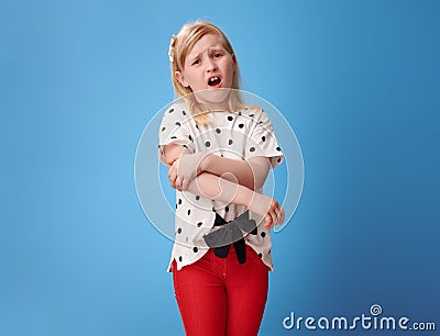 Unhappy modern child in red pants on blue with pain in hand Stock Photo