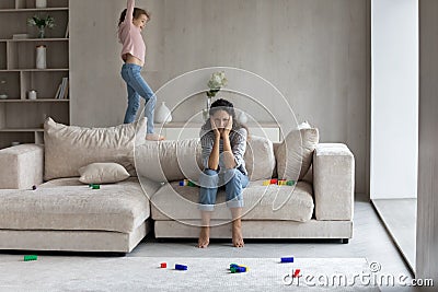 Unhappy mommy annoyed by hyperactive loud kid daughter. Stock Photo