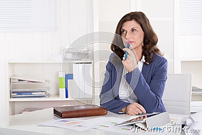 Unhappy older pensive business woman sitting at desk. Stock Photo