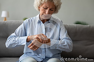 Unhappy older woman massaging wrist, feeling pain in joint Stock Photo