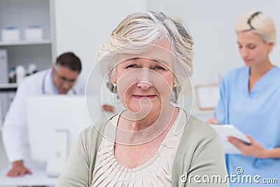 Unhappy patient with doctor and nurse working in background Stock Photo