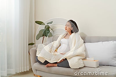 Unhappy Pregnant Lady suffering from cold sitting on coach Stock Photo