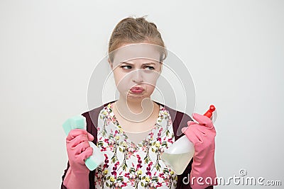 Unhappy sad young caucasian girl woman with rubber gloves, sponge and sprayer, cleaning the house Stock Photo