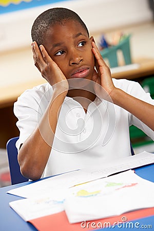 Unhappy Schoolboy Studying In Classroom Stock Photo