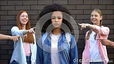 Unhappy schoolgirl looking camera, teenagers pointing fingers, bullying victim Stock Photo