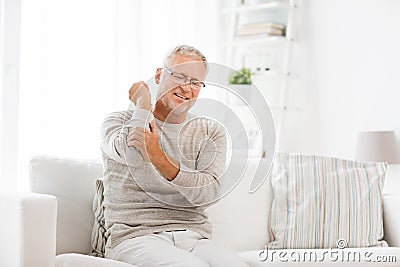 Unhappy senior man suffering elbow pain at home Stock Photo
