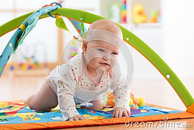 Unhappy seven months baby girl crawling on colorful playmat Stock Photo