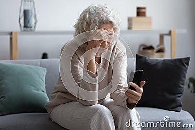Unhappy stressed mature middle aged woman looking at phone screen Stock Photo