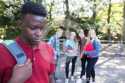 Unhappy Teenage Boy Being Gossiped About By School Friends Stock Photo