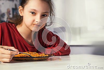 Unhappy tired kid girl does not want eat the tasty spaghetti on the dinner on the home kitchen. Closeup Stock Photo