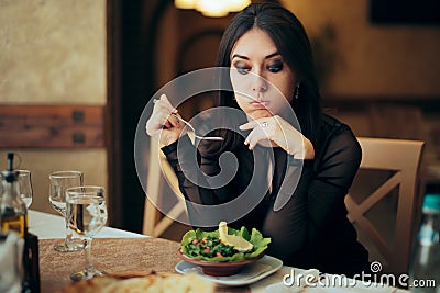 Unhappy Woman Eating a Salad by Herself in a Restaurant Stock Photo