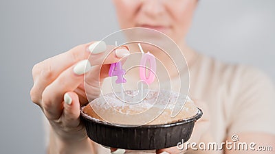 Unhappy woman holding a cake with candles for her 40th birthday. The girl cries about the loss of youth. Stock Photo