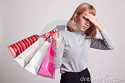 Unhappy young Asian woman with shopping bags and credit card. Stock Photo