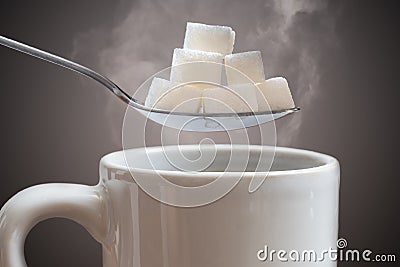 Unhealthy eating concept. Many sugar cubes above hot cup of tea or coffee Stock Photo