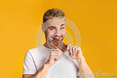 Unhealthy food. Ironic millennial man eating chocolate Stock Photo