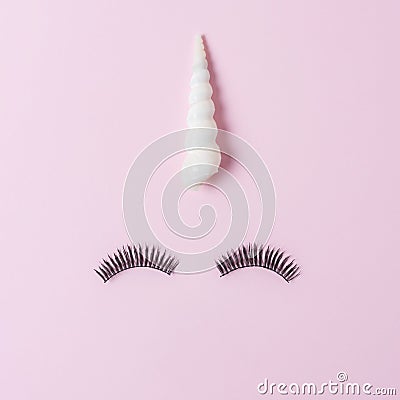 Unicorn face made of seashell with eyelashes on pastel pink background. Summer minimal concept Stock Photo