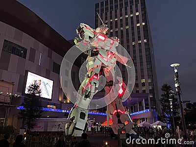 Unicorn Gundam standing in front of the Diver City Tokyo Plaza at night Editorial Stock Photo