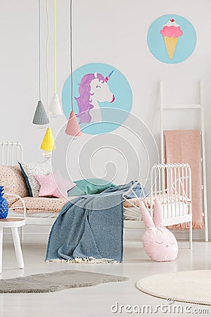 Unicorn and ice-cream posters on the wall and lamps above a bed Stock Photo