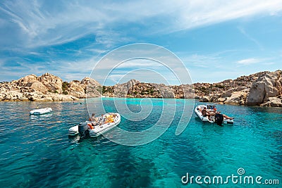 Tourists on small boats in an emerald water gulf - La Maddalena National Park - Parco Nazionale Arcipelago di La Stock Photo