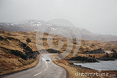 Unidentified car driving on a road going through Scottish Highlands near Lochinver, Scotland. Stock Photo