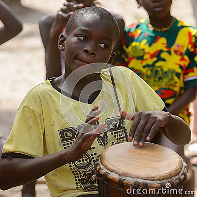 Unidentified Diola boy plays on drums in Kaschouane village. Di Editorial Stock Photo