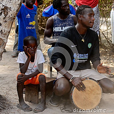 Unidentified Diola man plays on drums in Kaschouane village. Di Editorial Stock Photo