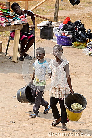 Unidentified Ghanaian kids carry buckets on the street in Elmin Editorial Stock Photo