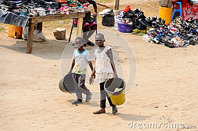 Unidentified Ghanaian kids carry buckets on the street in Elmin Editorial Stock Photo