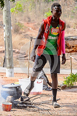 Unidentified Ghanaian man in colored clothes cooks on fire. Editorial Stock Photo