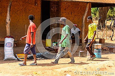 Unidentified local three men walk in a village in Guinea Bissau Editorial Stock Photo