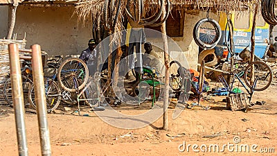 Unidentified local two men repair bicycles in a village in Guin Editorial Stock Photo