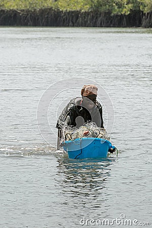 Unidentified local woman pulls a basin along the water in a vil Editorial Stock Photo