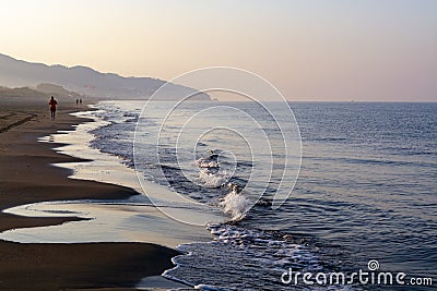 Unidentified man jogging in orange sportswear on sandy beach on sinrise over sea or ocean Stock Photo