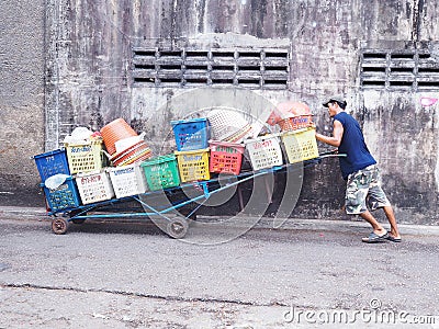 An unidentified man pushes barrow with many fruit baskets Editorial Stock Photo