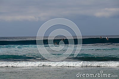 Unidentified man on surf board waiting for wave in blue water back view. Young Boys Waits the Waves. Surfer waiting in line for a Stock Photo