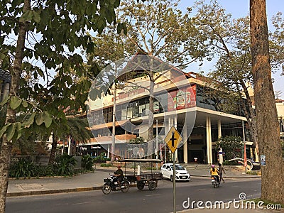 Unidentified pedestrian, bikers, and a car on a street junction near modern building with columns and glass walls Editorial Stock Photo