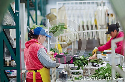Unidentified people working inside of a flower factory on bunch of blossoming beautiful roses bouquets, empaqued and Editorial Stock Photo