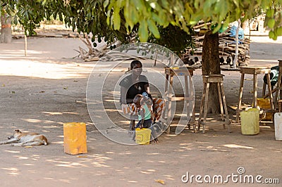 Unidentified Senegalese woman sits on the chair while her baby Editorial Stock Photo