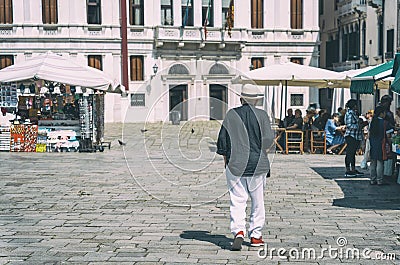 Unidentified senior tourist or local walking on the cobblestone alleys in Venice, Italy. Vintage picture Editorial Stock Photo